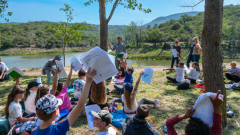 élèves assis dans l'herbe au bord du lac de l'Avellan lors d'une sortie scolaire